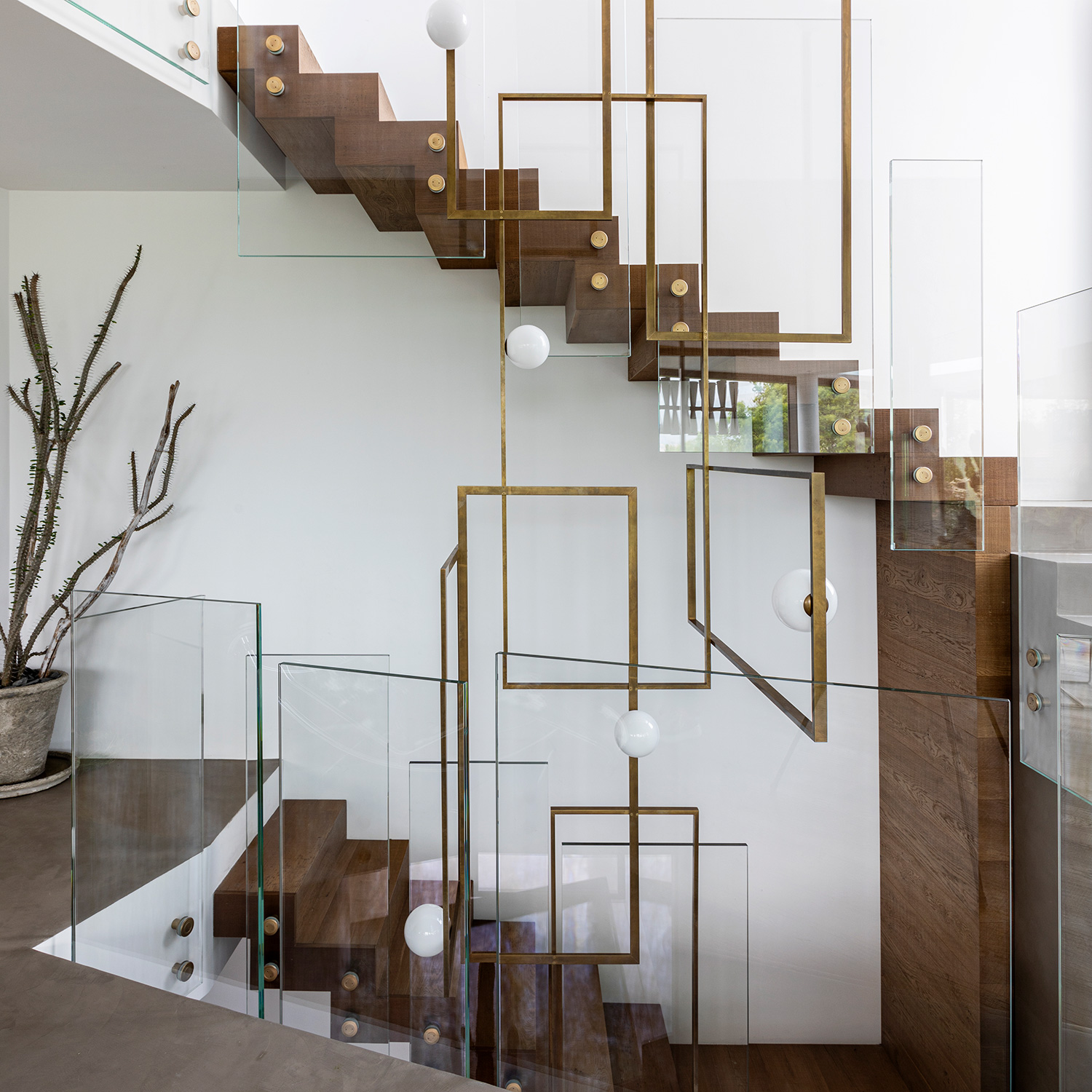 Die rahmenlosen Glasgeländer der Holztreppe geben den Blick auf das maßgefertigte Lichtkunstwerk aus Messing und Muranoglaskugeln frei (Venicem).